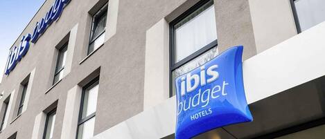 A hotel building with a sign for 'ibis budget hotels' and a clear sky.
