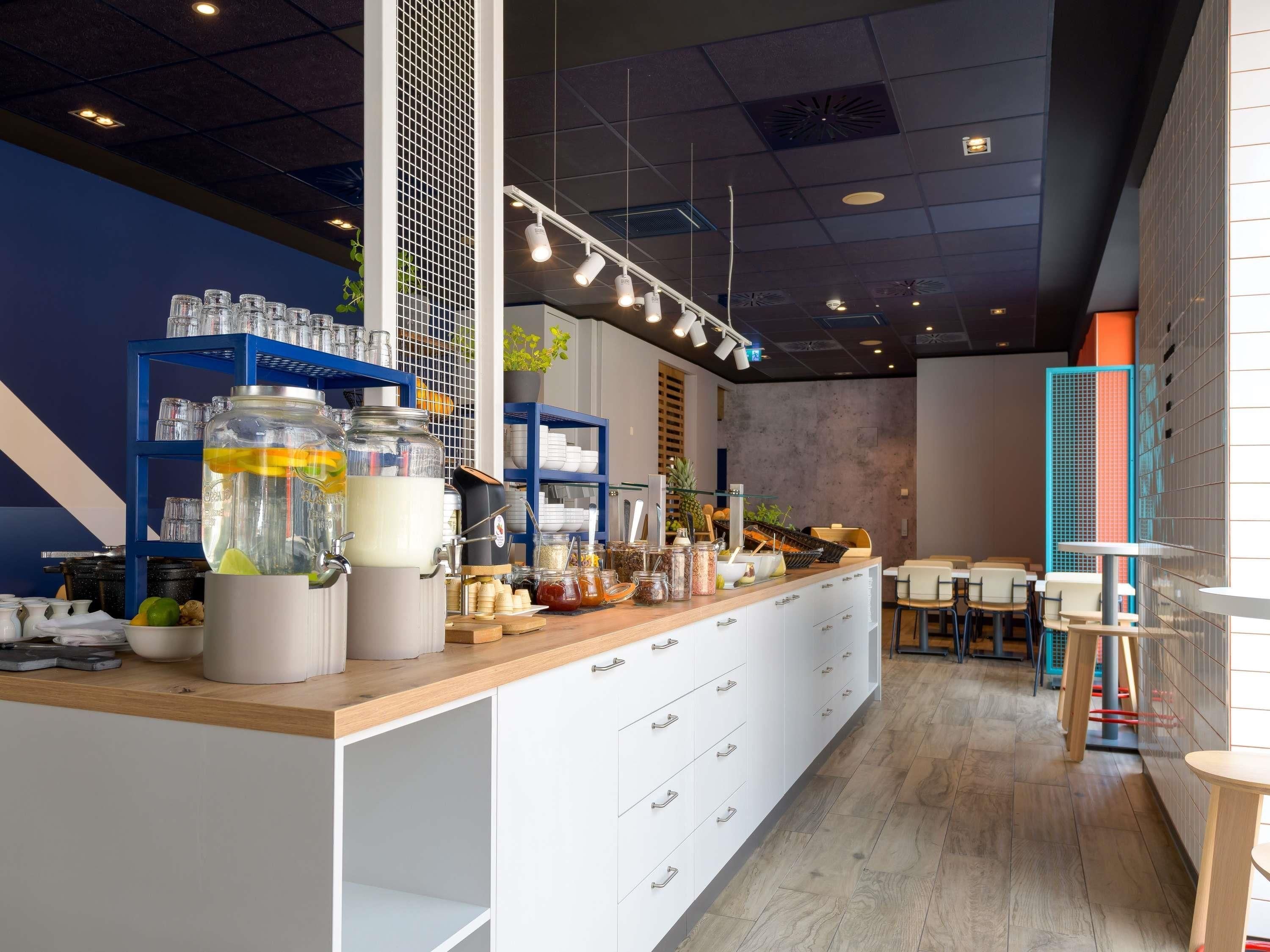 Un interior de cafetería moderna con mostrador de madera, armarios blancos y estantería azul.