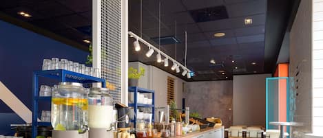 Un interior de cafetería moderna con mostrador de madera, armarios blancos y estantería azul.