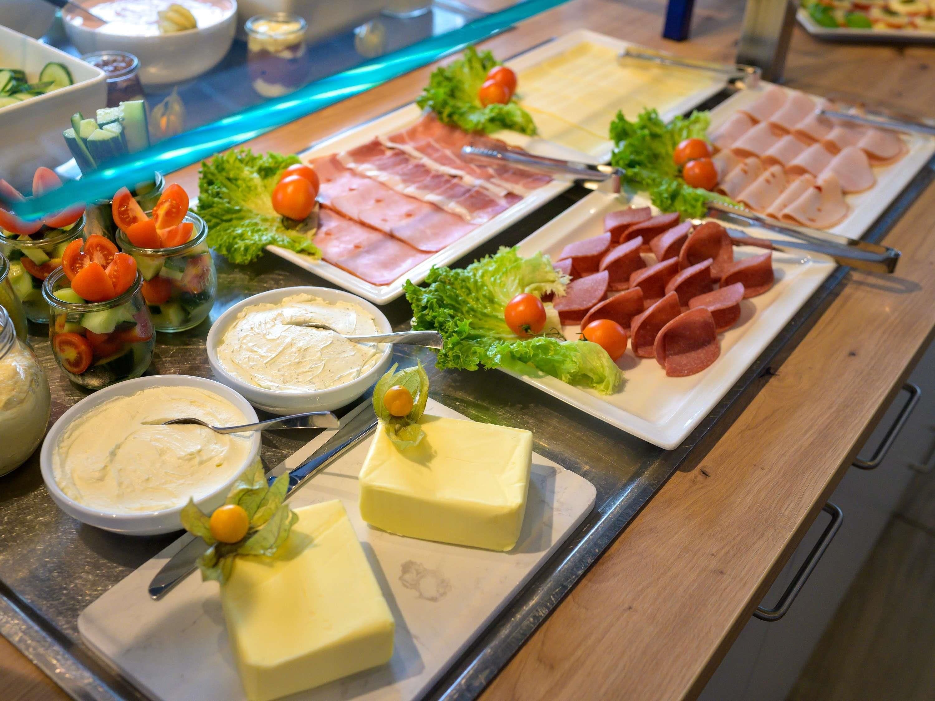 A buffet with various food items including sliced meats, cheese, and dips.