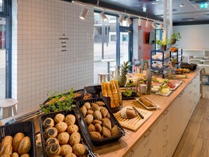 A buffet area with various food items and bread baskets.