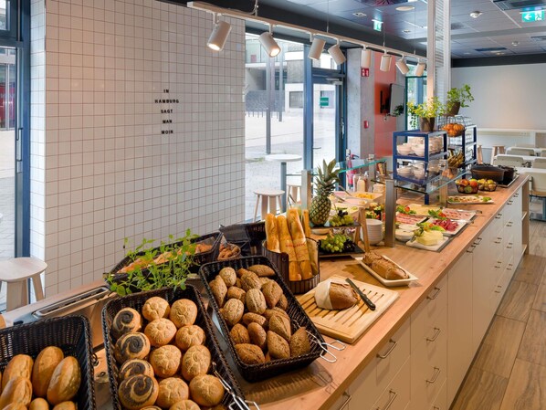 A buffet area with various food items and bread baskets.