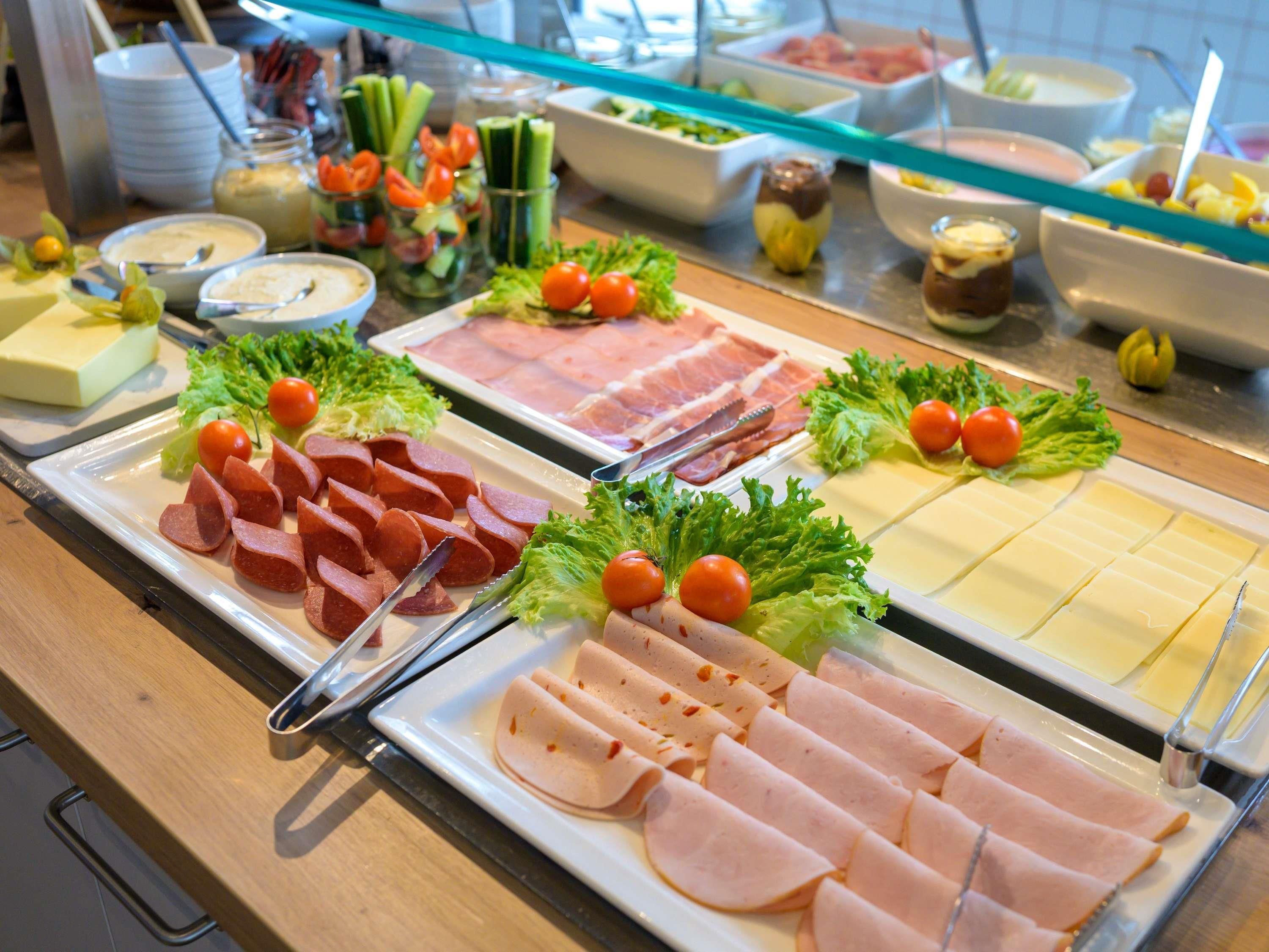 Un buffet proposant une variété d’aliments, notamment des viandes en tranches, des fromages et des légumes.