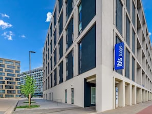Moderni hotellirakennus, jossa on selkeästi näkyvä «ibis budget» -kyltti, suuret ikkunat ja siisti, urbaani ympäristö.