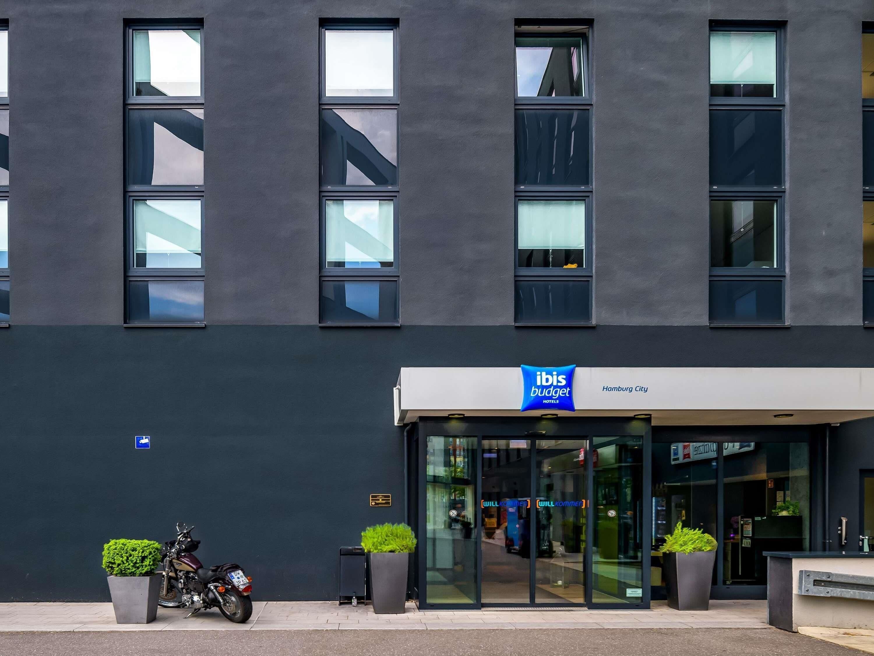 A modern building with a sign for 'Ibis Budget Hamburg City' hotel.