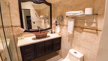 A bathroom with a large mirror, a sink with a decorative bowl, a toilet, and a towel rack with folded towels.