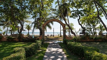 A pathway leading to a beach area with palm trees and a stone archway.