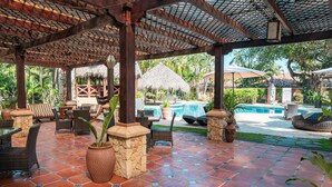 An outdoor patio with tiled flooring, wicker furniture, and a pool area.