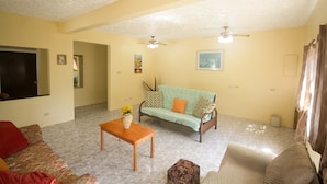 A living room with a sofa, a coffee table, and a TV. - Rocky Top Retreat (Negril)