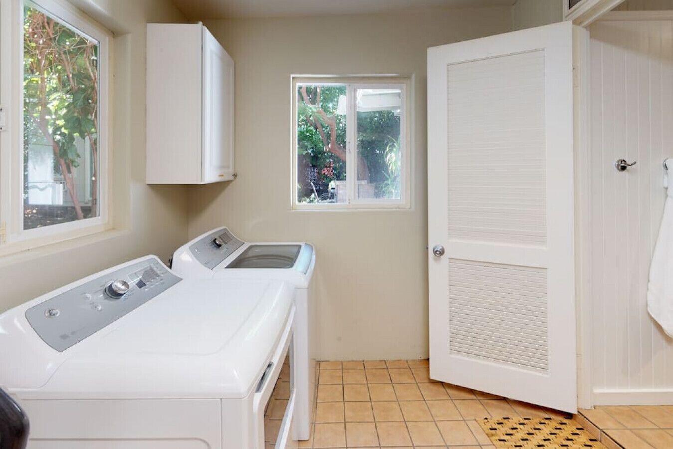 A laundry room with a washing machine, a dryer, a small window, and a door.