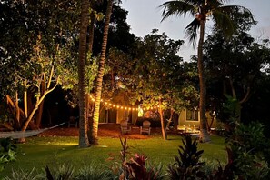 Ein Garten mit einer Hängematte, Lichterketten und einem Essbereich mit Stühlen und einem Tisch.