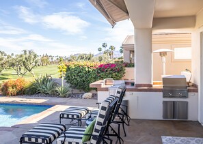 A patio with outdoor seating, a pool, and a barbecue area.