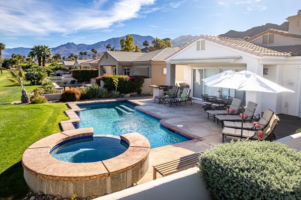 A residential property with a swimming pool, outdoor seating, and a view of mountains.