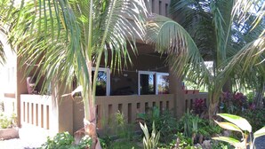 A building with a balcony, surrounded by various plants and a gravel pathway. - Waterfront Luxury 3 Bedroom w/ Pool and Dock (West End)