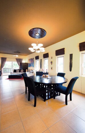 A spacious dining area with a round table, black chairs, and a ceiling light fixture.