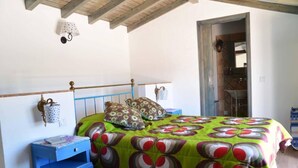 A bedroom with a bed, a nightstand, a lamp, and a door leading to a bathroom.