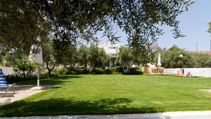 Un prato curato con un'amaca, un'altalena e un'area giochi con uno scivolo e una piccola struttura.