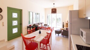 Una cucina luminosa con angolo pranzo, una porta verde e un lampadario moderno.