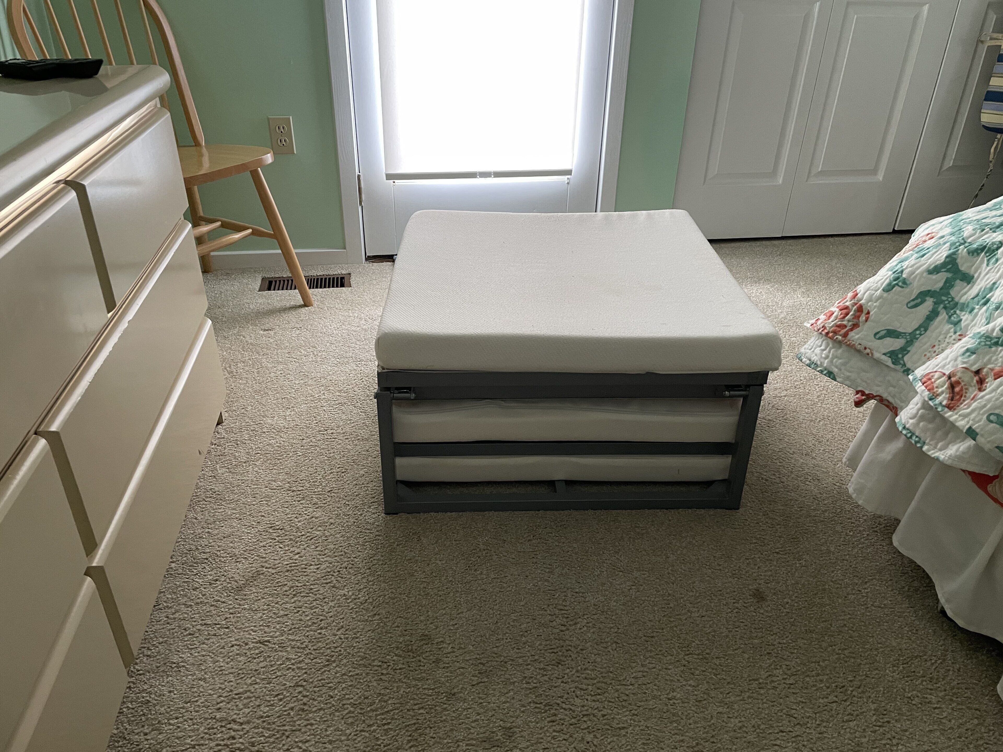 Een slaapkamer met een bed, een dressoir, een stoel en een raam.