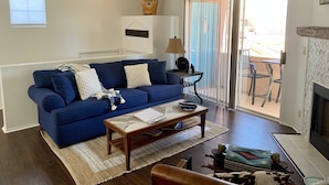 A living room with a blue sofa, a coffee table, and a fireplace.