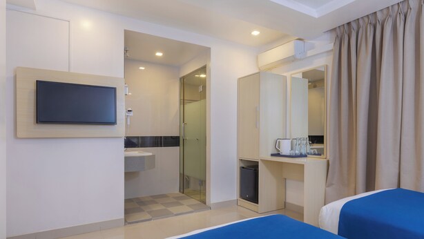 A hotel room with a bed, a TV mounted on the wall, a bathroom with a sink, and a mirror. - The White Harp Beach Hotel (Hulhumalé)