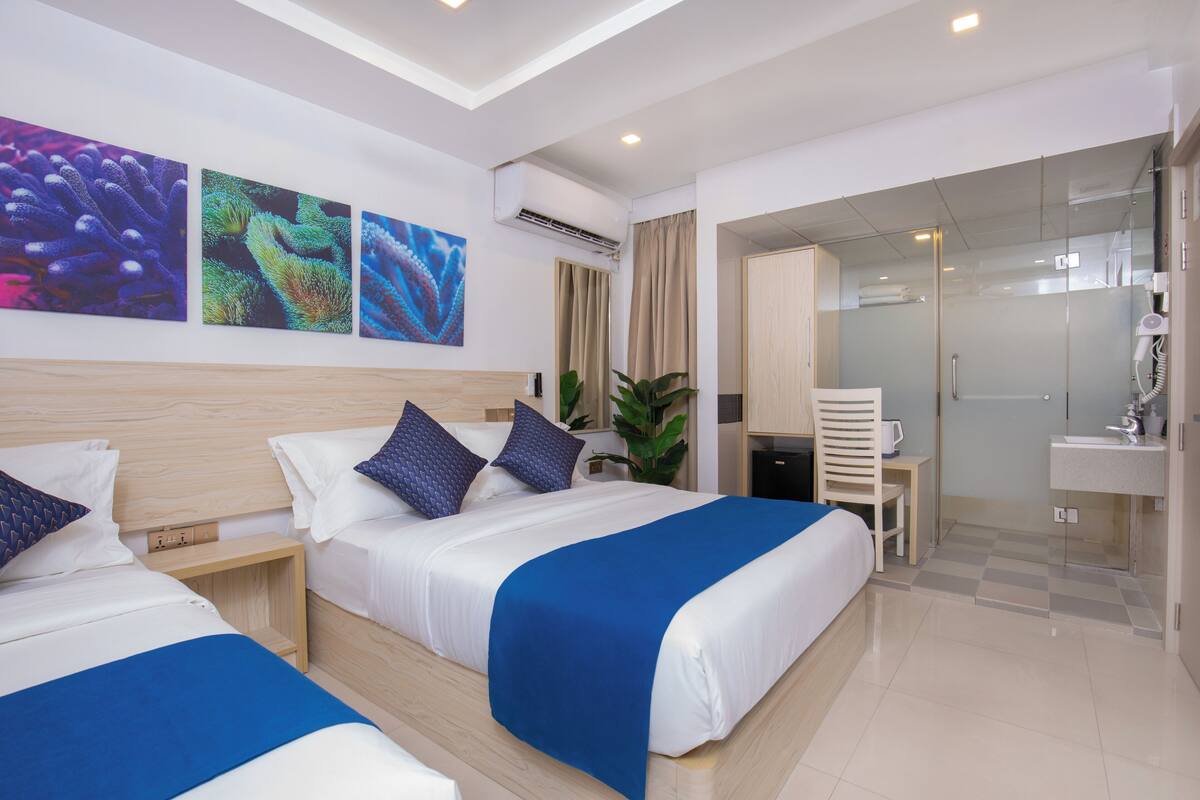 A hotel room with two beds, a desk, a shower, and a bathroom.