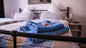 A neatly made bed with a blue blanket and pillows, a bedside table with a lamp, and a painting on the wall. - Sunny 4-star holiday home in Stralsund, the gateway to the island of Rügen (Stralsund)