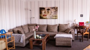 A living room with a sofa, coffee table, and a side table with a lamp. - Sunny 4-star holiday home in Stralsund, the gateway to the island of Rügen (Stralsund)