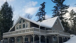 Une grande maison à deux étages, dotée d’un porche et d’un garage.