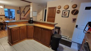 Une cuisine avec des meubles de rangement en bois, une machine à café et une poubelle.