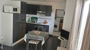 Una cocina compacta con armarios oscuros, un microondas, una estufa y una lavadora.