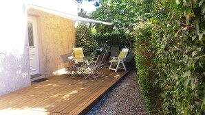 Un patio exterior con terraza de madera, una mesa y sillas.