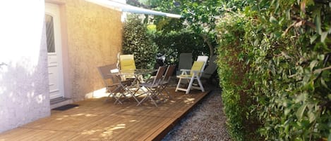 An outdoor patio with a wooden deck, a table, and chairs.