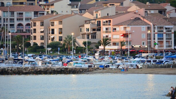 Un puerto deportivo con barcos y una hilera de edificios de varios pisos con balcones.