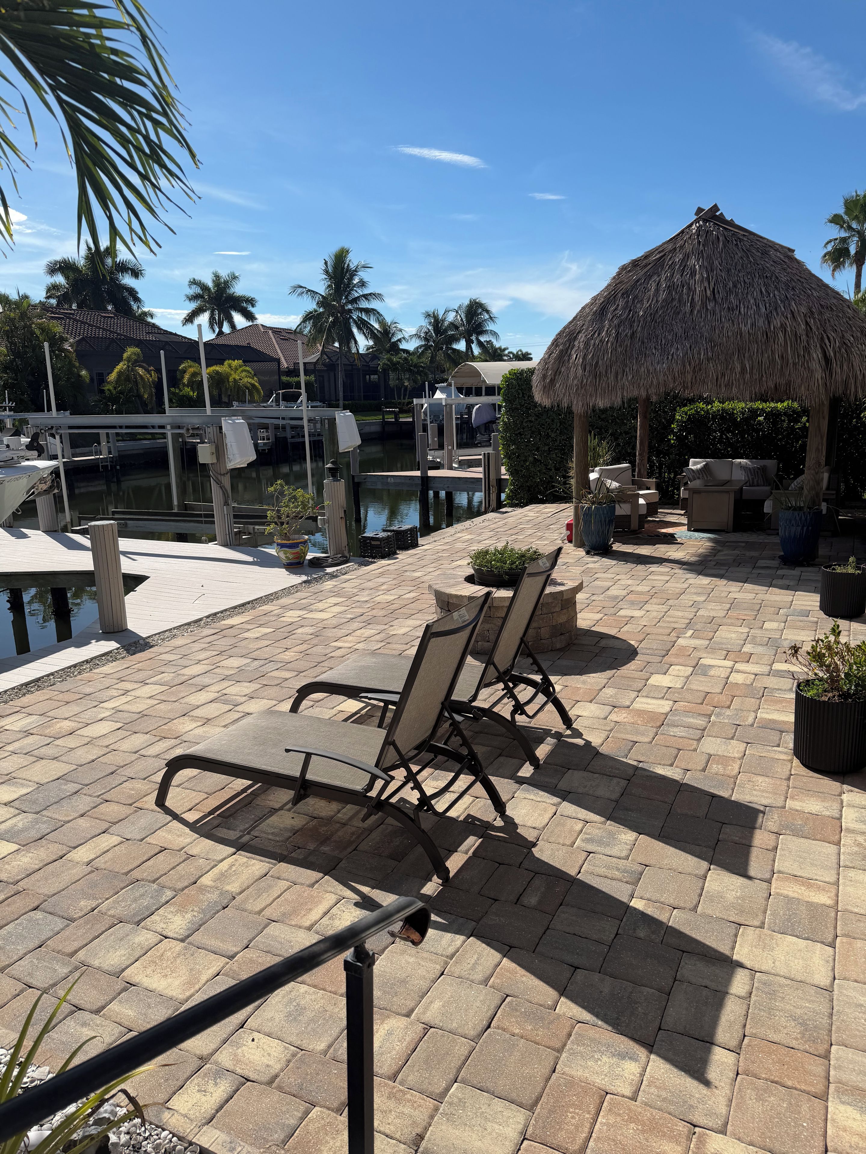 A patio area with outdoor seating, a thatched-roof structure, and a view of the marina.