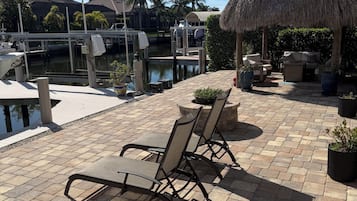 A patio area with outdoor seating, a thatched-roof structure, and a view of the marina.