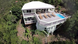 A two-story house with a balcony and a pool. - Fish Tales a Caribbean Cottage style home with a Pool, walk to Reef Bay Beach (St John)