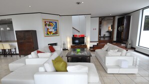 Un salon moderne avec un canapé d’angle, une table basse et un téléviseur à écran plat.
