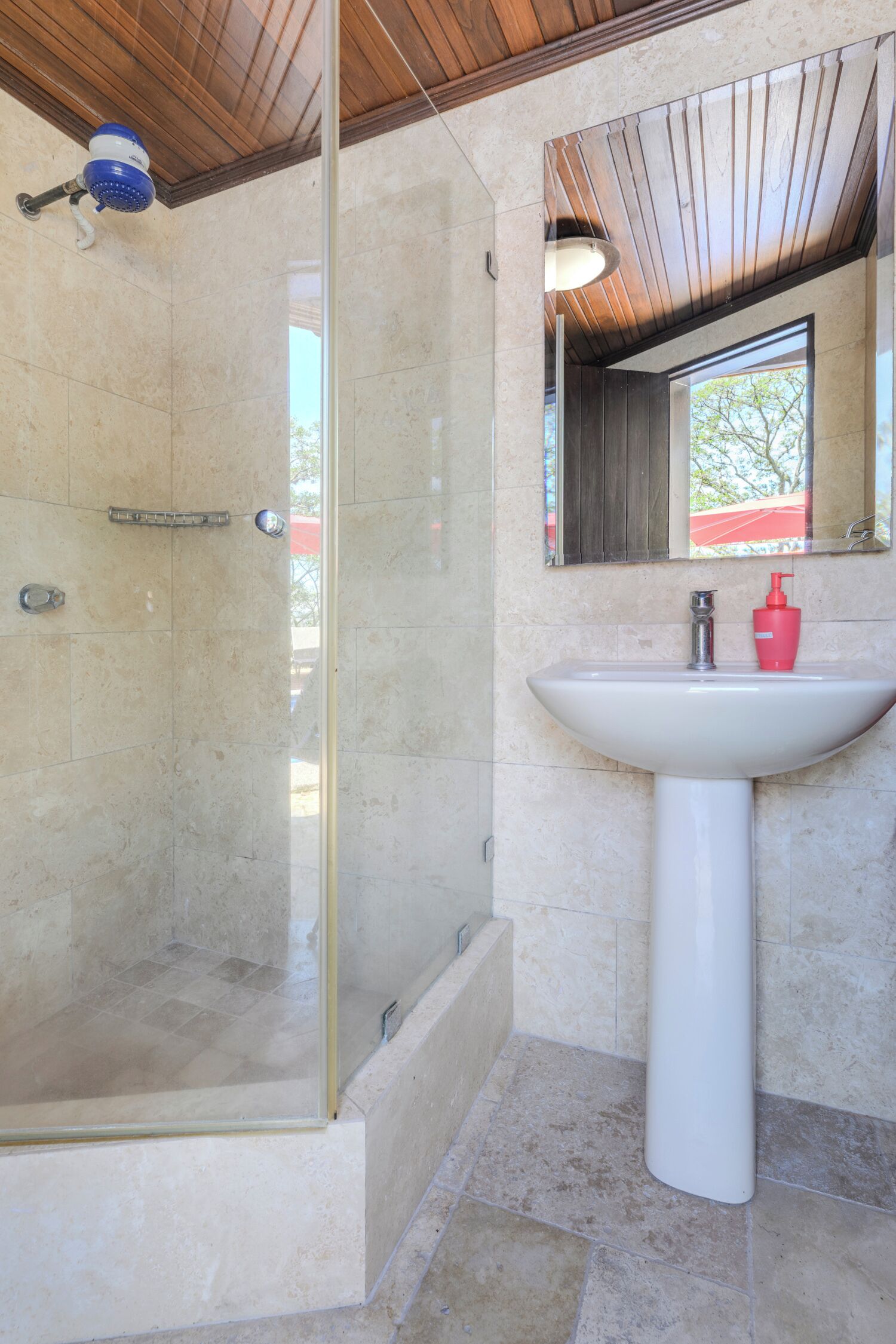 A bathroom with a glass-enclosed shower, a white sink, and a mirror above it.