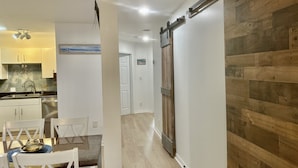 A modern kitchen with white cabinets, a stainless steel sink, and a wooden dining table with chairs.