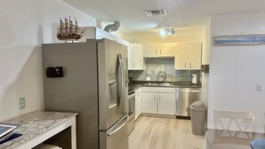 A compact kitchen with a refrigerator, sink, and a small dining area with a table and chairs.