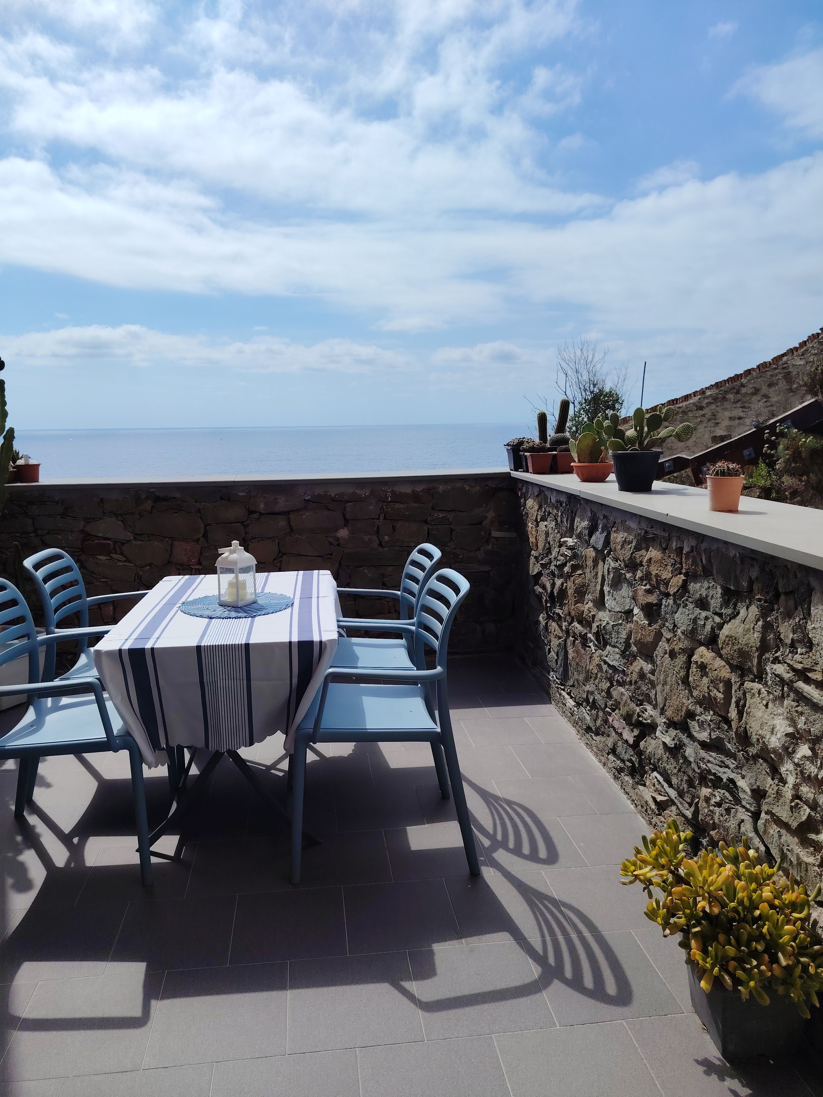 An outdoor patio with a table and chairs, a stone wall, and potted plants.