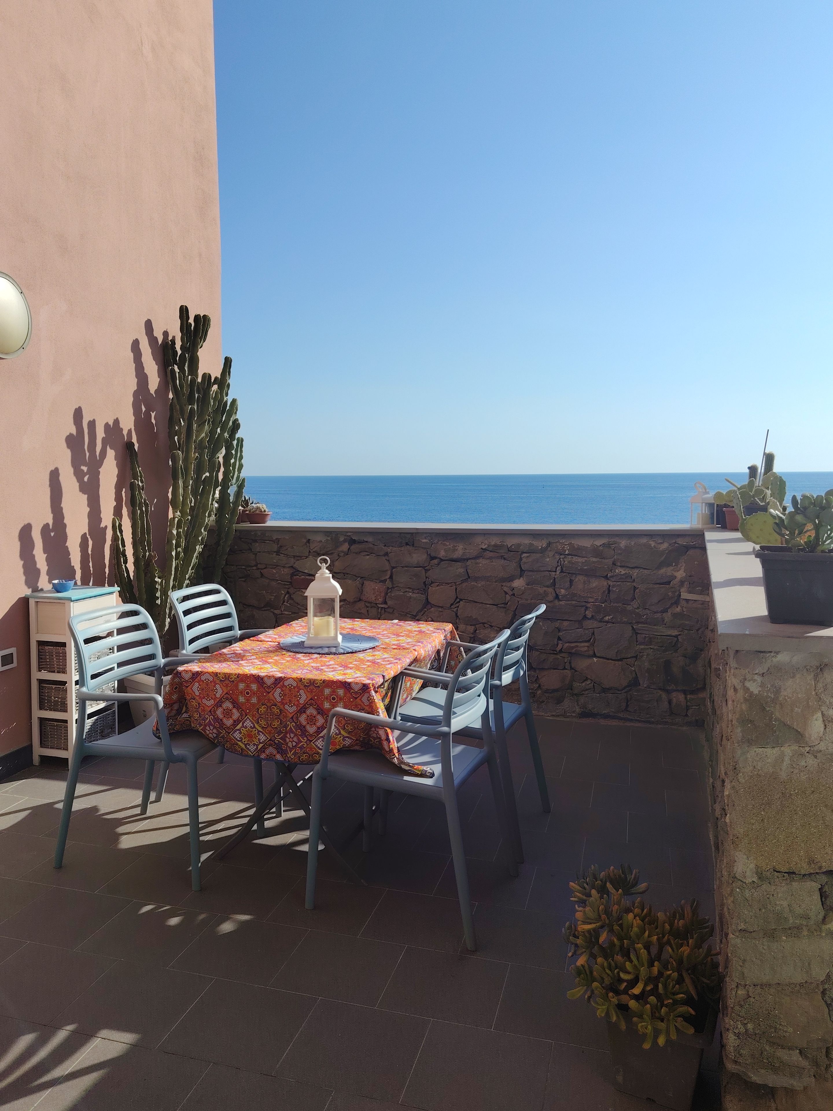 Eine Außenpatio mit Tisch und Stühlen, einer Kaktee und Blick aufs Meer.