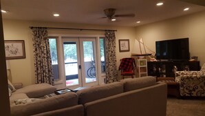 Una sala de estar con un sofá, sillones, un televisor y una bicicleta afuera de la puerta.