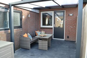 A patio area with a wicker sofa, a small table, and a glass door.