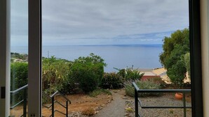 Blick vom Balkon auf eine Küstenlandschaft mit klarem Himmel und weiter Ferne.