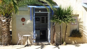 Un petit espace extérieur aménagé avec une table et des chaises, une piscine et l’entrée d’un bâtiment.