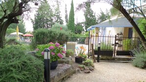 Un jardin avec un chemin de gravier, des plantes en pot et une clôture en métal.