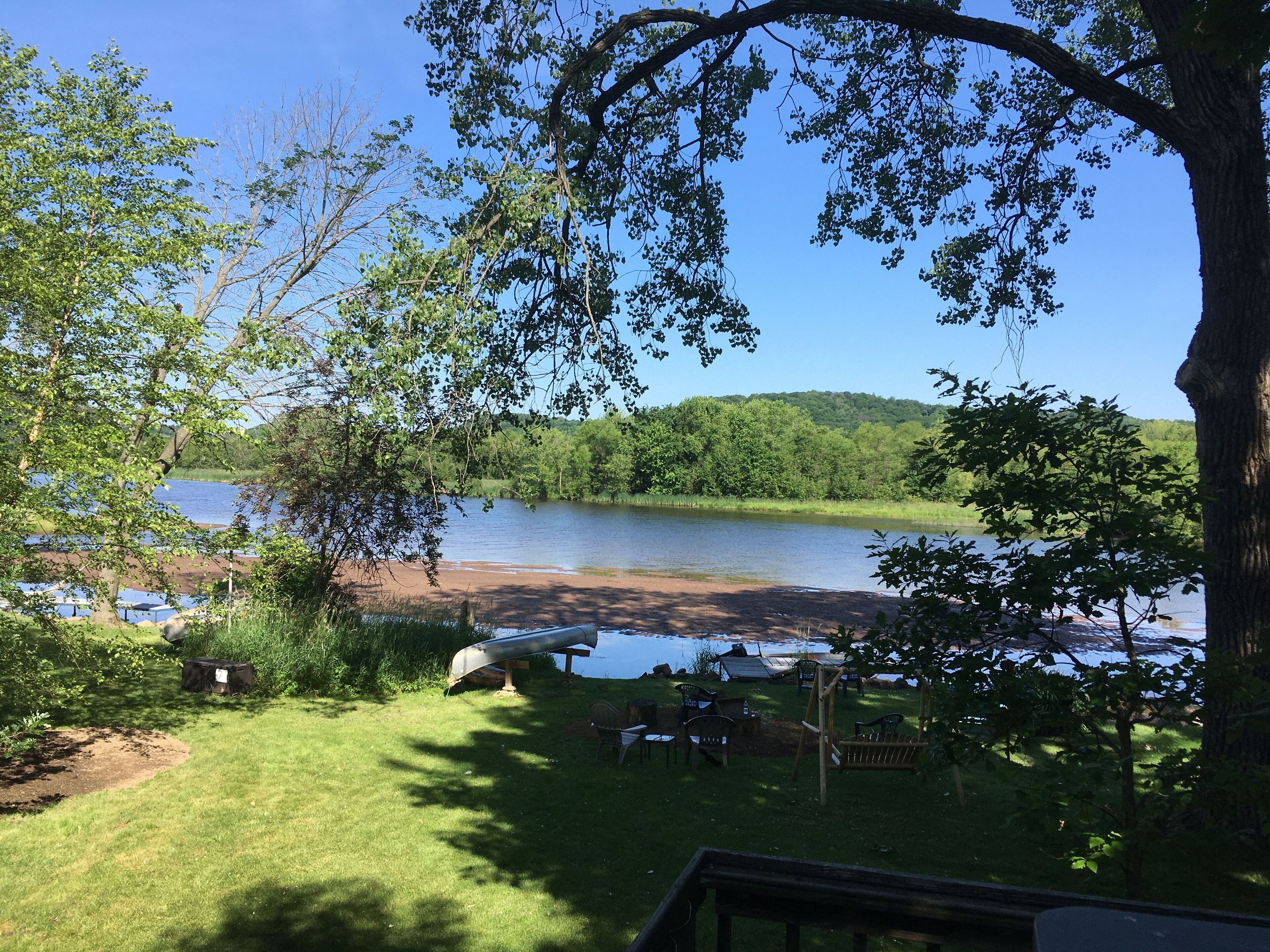 A lakeside view with a grassy area, picnic tables, and a wooden deck.