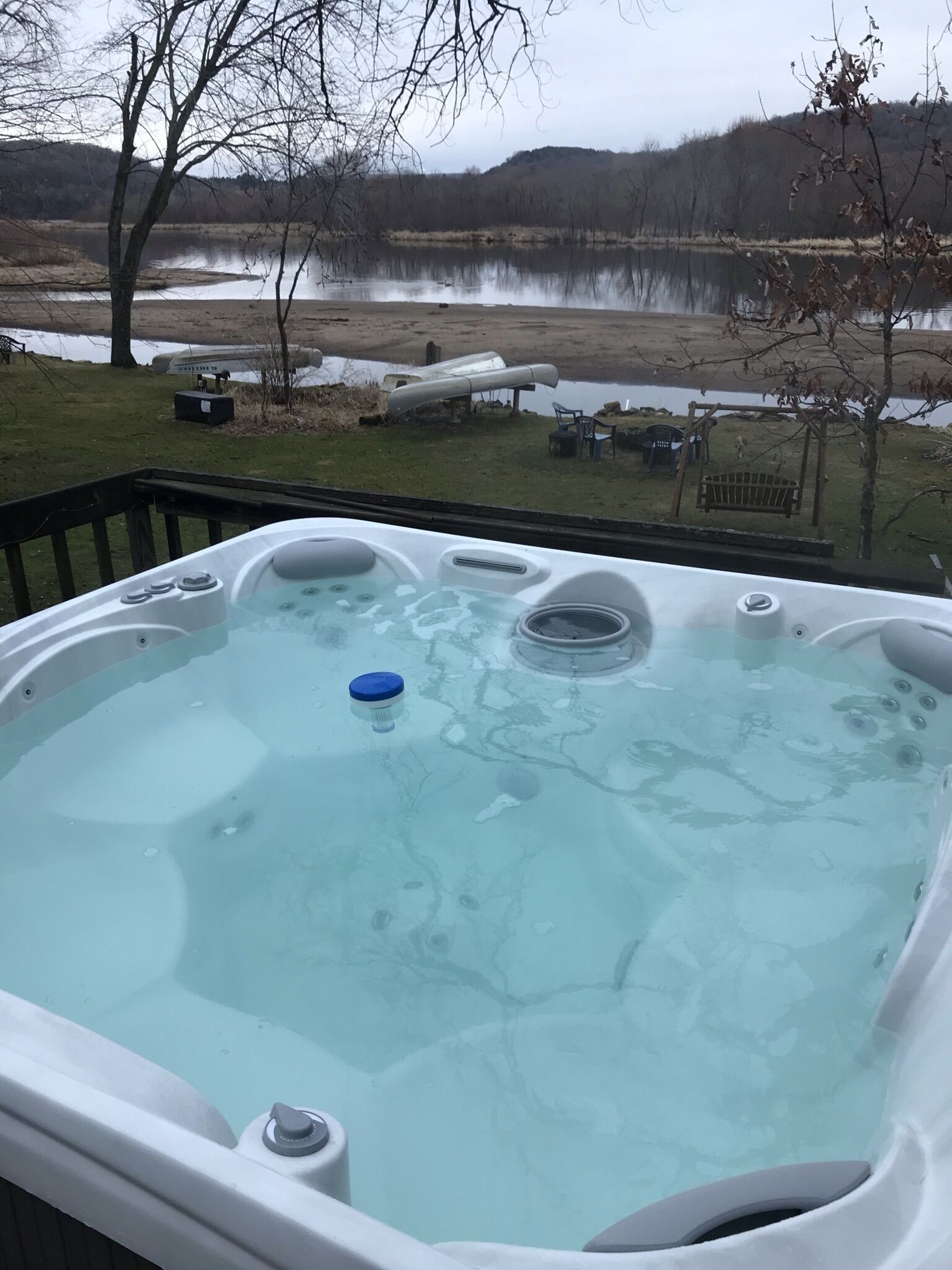 Ein Whirlpool mit Blick auf einen See und Bäume im Hintergrund.